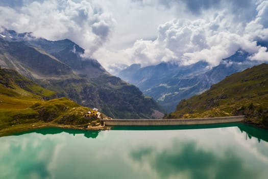 Inspiring alpine landscape with beautiful calm lake with dam