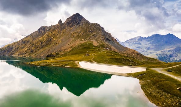 Inspiring alpine landscape with beautiful calm lake with dam