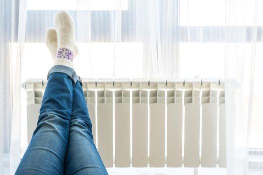 Woman laying on floor with feet raised up on radiator for warming
