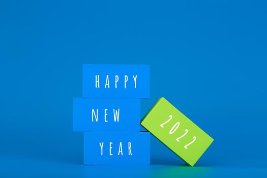 Happy New Year 2022 blue minimal trendy concept. Modern elegant composition with blue toy blocks with written Happy New Year text on blue background