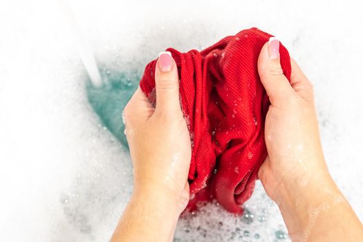 Female hands washing color clothes in basin