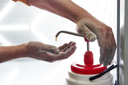 Mechanic washing dirty hands with a soap after work