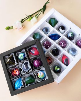 Gift box of handmade chocolates. Geometric and space design. Box on a light background. Sweets and candies close-up. Vertical photo