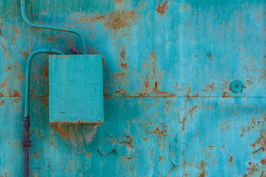 turquoise painted cracked and rusted flat steel sheet with natural gas meter and distributor box.