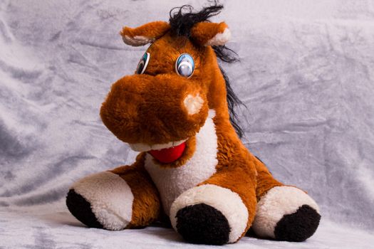 Soft plush toy horse on gray background close up