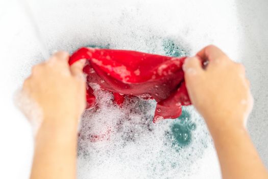 Female hands washing color clothes in basin