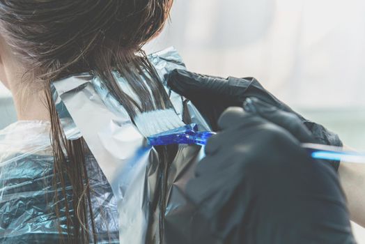woman having hair foiled while coloring in a hair salon