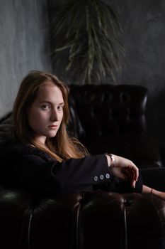 portrait of confident woman in black in dark room. pensive serious people. business woman. feminine. millennial people.