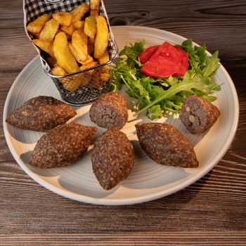 Traditional kebbe and pita bread on big round plate in lebanese restaurant. High quality photo