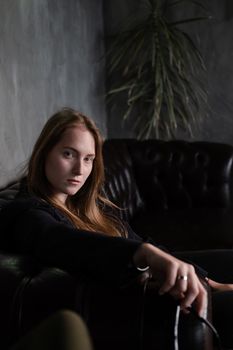 portrait of confident woman in black in dark room. pensive serious people. business woman. feminine. millennial people.