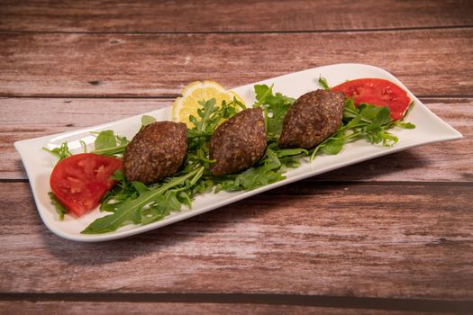 Traditional kebbe and pita bread on big round plate in lebanese restaurant. High quality photo