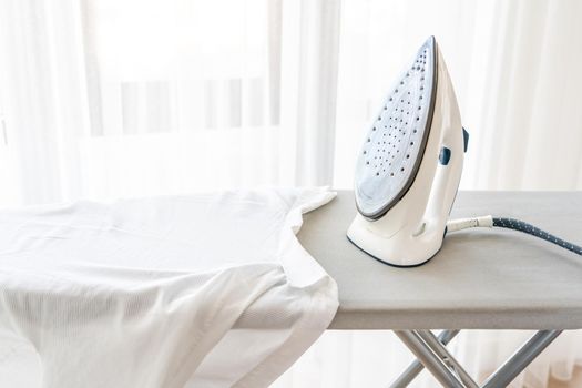 Steam generator iron standing on ironing board near panoramic window