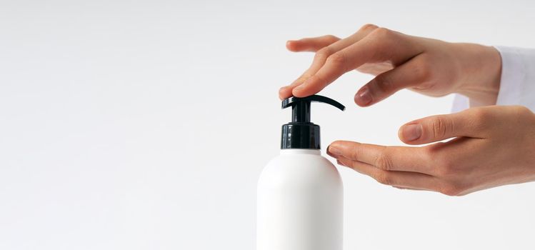 Woman hands pushing pump plastic soap bottle on white background