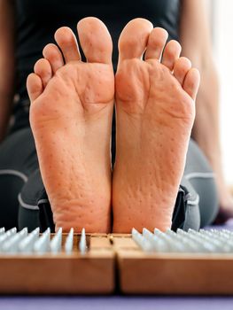Feet and wooden board with sharp metal nails. Sadhu foot board. Yoga relaxation practice training tool.