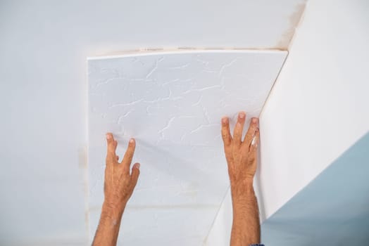 adhesive plaster application of styrofoam ceiling tiles of a home kitchen