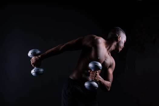 Athletic african american man topless, big muscles, a dark background studio