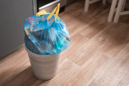 Full garbage trash in a trash bag with strings can standing at room