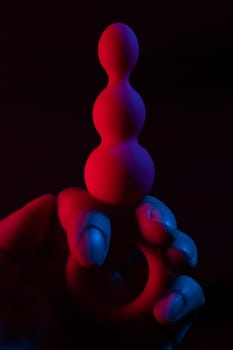 Woman holding anal beads in neon pink blue light