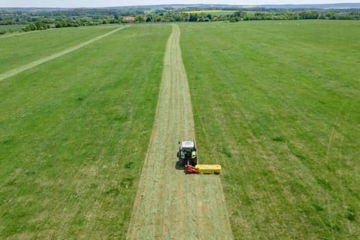 Grass is evenly mowed by a tractor rotary cutter on field in the countryside. Panoramic view from above of farmer's work in the field.