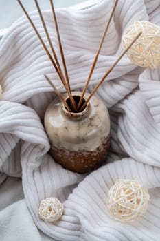 Aroma reed diffuser. Bottle container with wood stick diffusers Essential oils to scent your home fragnance concept autumn holidays at cozy home on the windowsill Hygge aesthetic atmosphere on knitted white sweater. Still life of micro moment candid slow living. Mental health wellbeing exercises Raining Outside