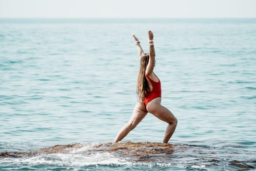 Woman sea yoga. Back view of free calm happy satisfied woman with long hair standing on top rock with yoga position against of sky by the sea. Healthy lifestyle outdoors in nature, fitness concept.