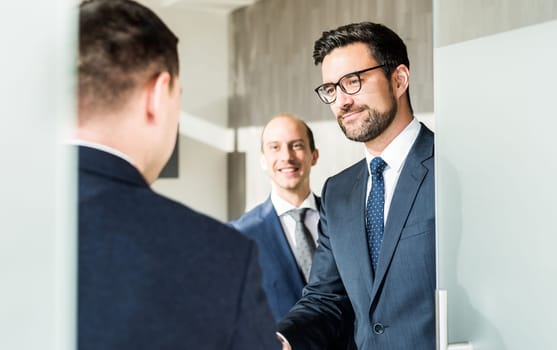 Group of confident business people greeting with a handshake at business meeting in modern office. Closing the deal agreement by shaking hands. Business and entrepreneurship success concept.