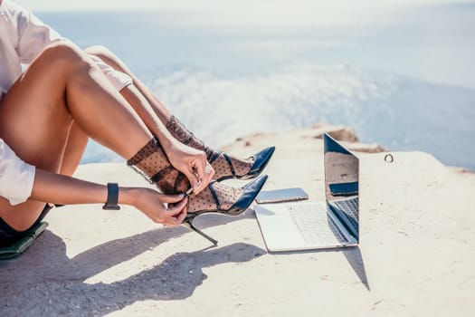 Happy girl doing yoga with laptop working at the beach. beautiful and calm business woman sitting with a laptop in a summer cafe in the lotus position meditating and relaxing. freelance girl remote work beach paradise