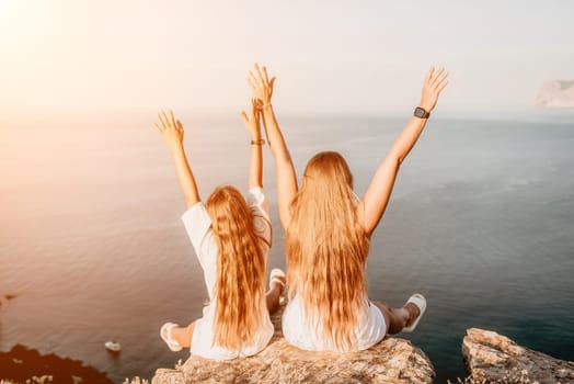 Close up portrait of mom and her teenage daughter hugging and smiling together over sunset sea view. Beautiful woman relaxing with her child.