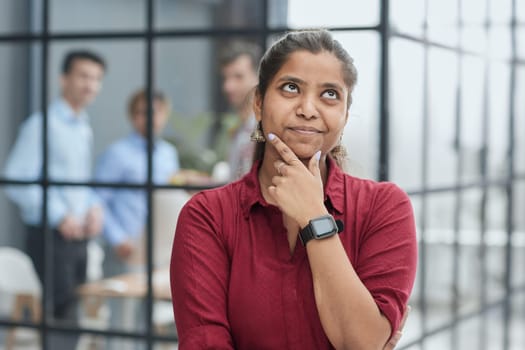 Dreamy young Indian female employee look in distance thinking or pondering,