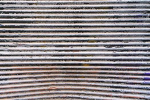 Detail of a wavy metal clasp, old and very textured with horizontal lines. In light tones.