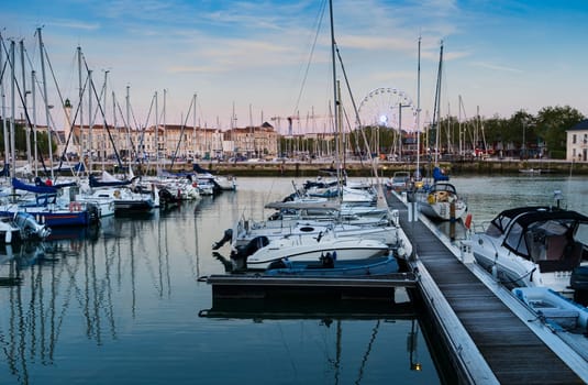 View of the harbor of the French city of La Rochelle with yachts in the foreground at sunset on a summer day.