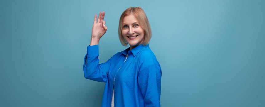 close-up of a mature woman in a blue shirt with an idea on a blue background with copy space.