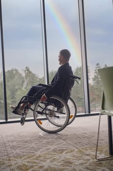 Successful businessman with a disability enjoys a fun-filled moment in his wheelchair, surrounded by the modern ambiance of an inclusive office, while the vibrant rainbow in the background symbolizes diversity and empowerment.