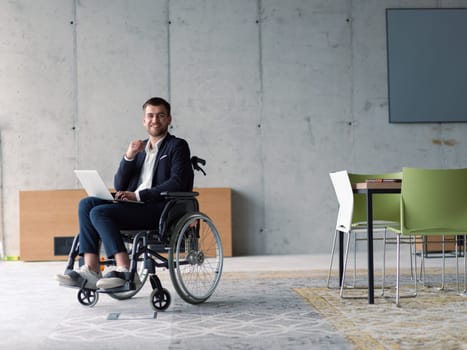 A businessman with disability in a wheelchair using laptop in a modern office . High quality photo