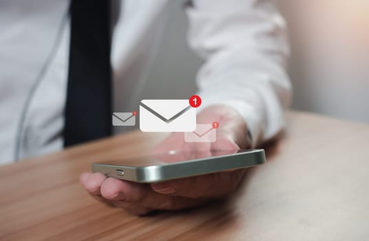 businessman holding a phone along with the e-mail icon. New email notification ideas for business email communication and digital marketing. The inbox receives electronic message notifications. internet technology