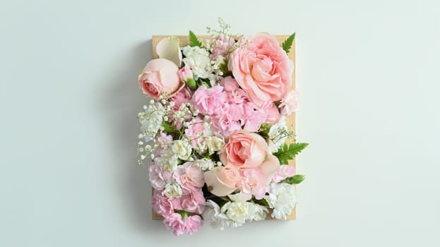 Wooden crate full of pastel colors flowers with pink rose and carnation on white background.
