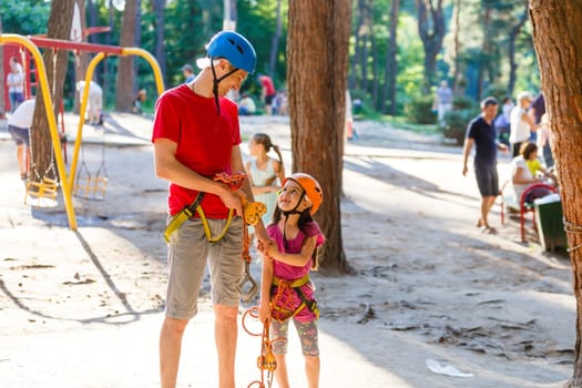 male instructor helps the child on the rope road in the training camp