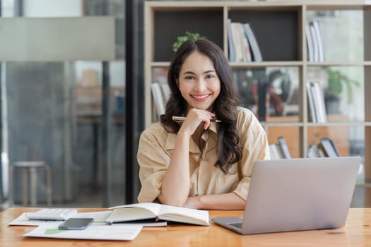 Business woman, portrait and smile at desk in office for paperwork, laptop. Happy, young or confident female worker with pride planning project at table in startup company.