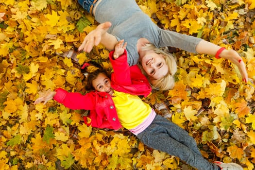 Young mother playing with her daughter in autumn park.