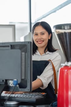 Cheerful shop assistant using digital device for payment.