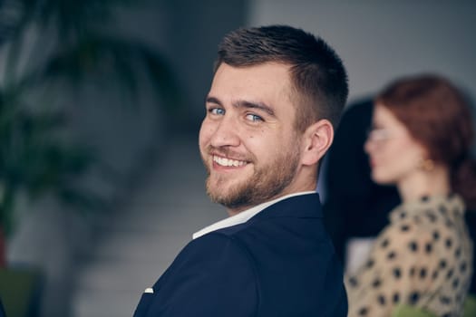 A smiling entrepreneur sits in a modern office, actively participating in a business meeting, radiating confidence and professionalism