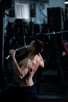 A man does a chest pulldown in the gym