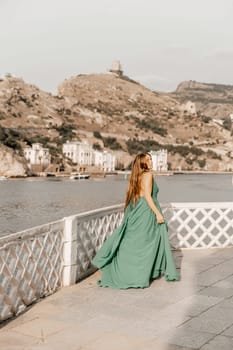 Woman sea trevel green dress. Side view a happy woman with long hair in a long mint dress posing on a beach with calm sea bokeh lights on sunny day. Girl on the nature on blue sky background