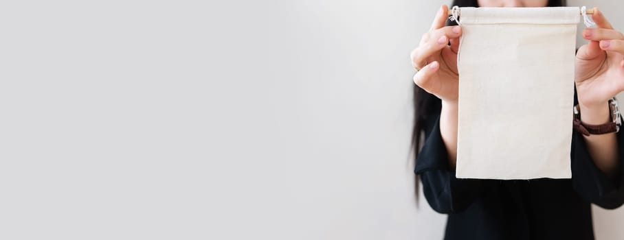 Young business woman in a black suit shows a blank white billboard on a white isolated background. Place for the inscription on the poster. Banner