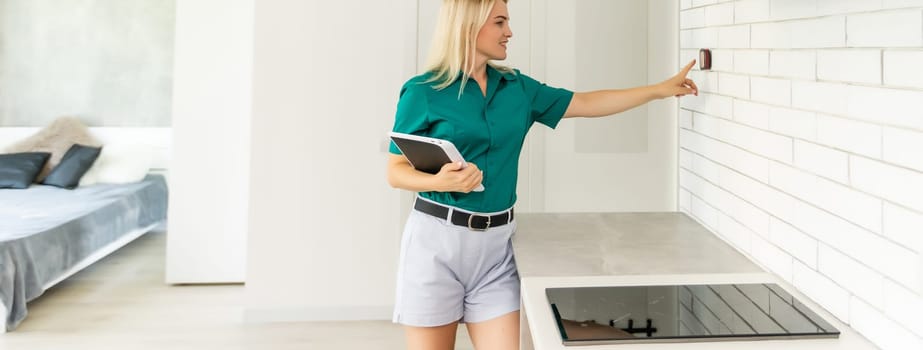 Smiling Woman Adjusting Thermostat On Home Heating System.