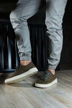 Close-up of male feet in green leather shoes. A young man is standing in leather stylish green sneakers in gray jeans. Summer men's shoes. Casual street style