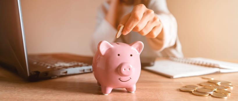 A young girl makes calculations, checks her finances, makes notes in a notebook and sets aside some of the funds, savings in a piggy bank for personal expenses and future development.