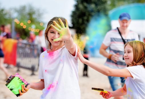 Pretty girls in indian traditional Holi festival with colorful powder having fun. Female teenager and preteen child enjoying positive holiday of India