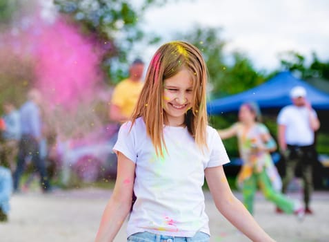 Preteen girl in indian traditional Holi festival with colorful powder having fun. Female child kid enjoying positive holiday of India