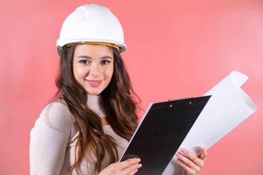 Smiling woman architect wearing white hardhat and and delighted expression enjoys job